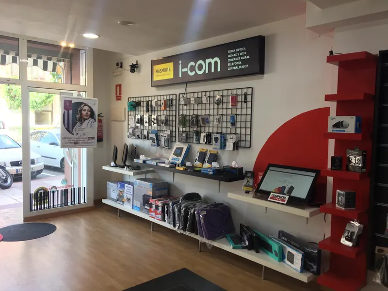 Vista interior de I-COM, con el rótulo de la tienda y expositores de productos.